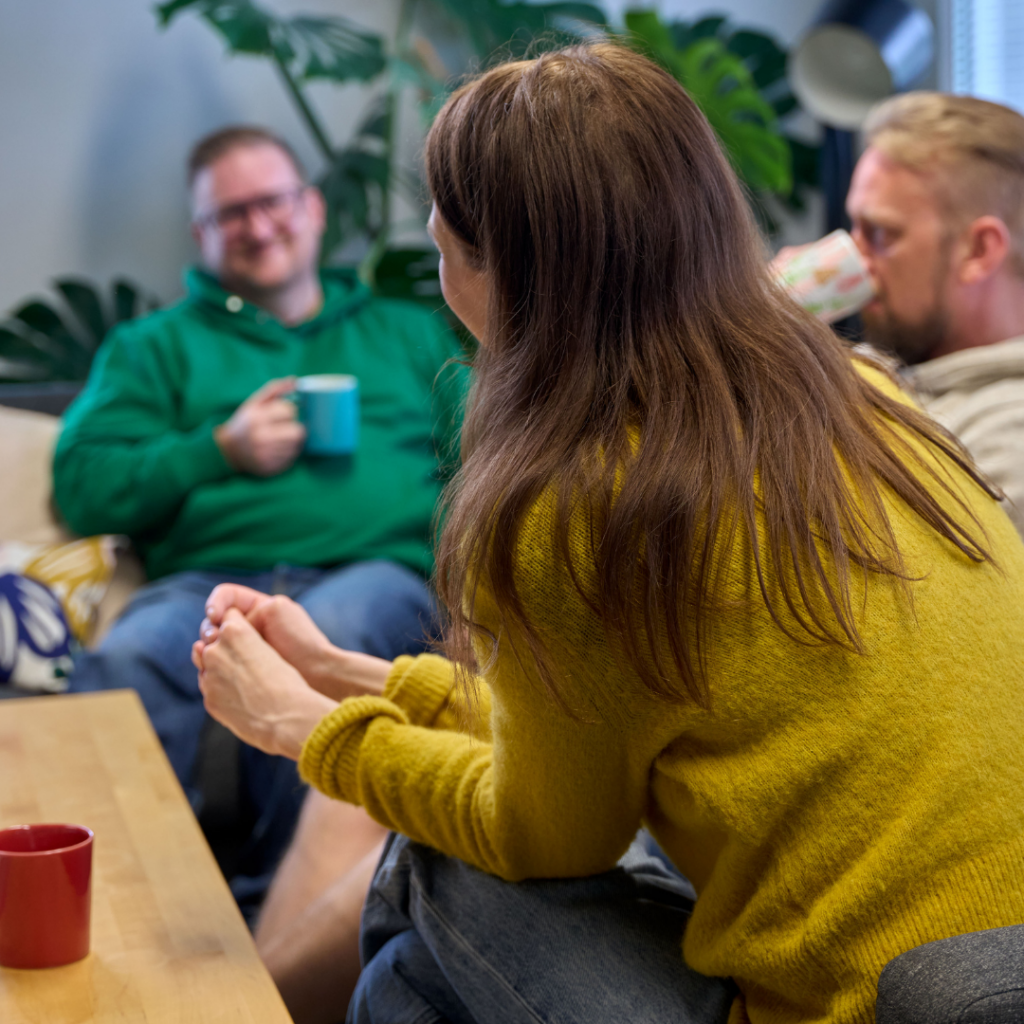 Kolme henkilöä keskustelevat sohvalla