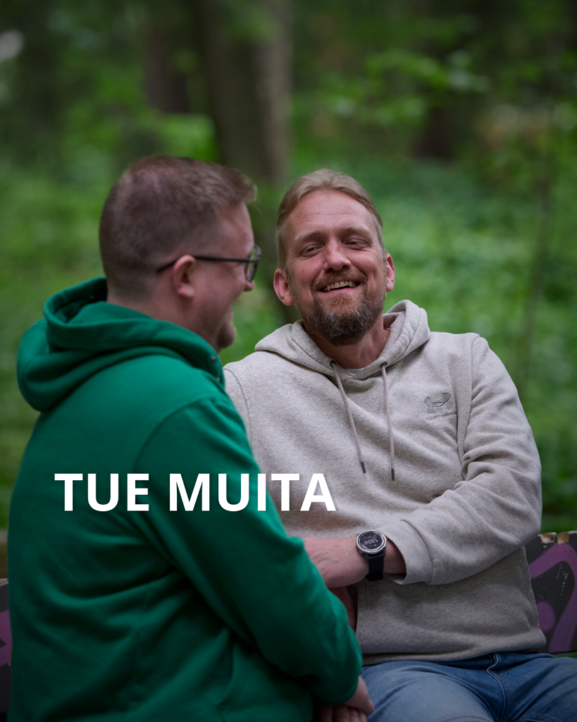 Kaksi henkilöä istuu puistonpenkillä ja nauraa. Tue muita